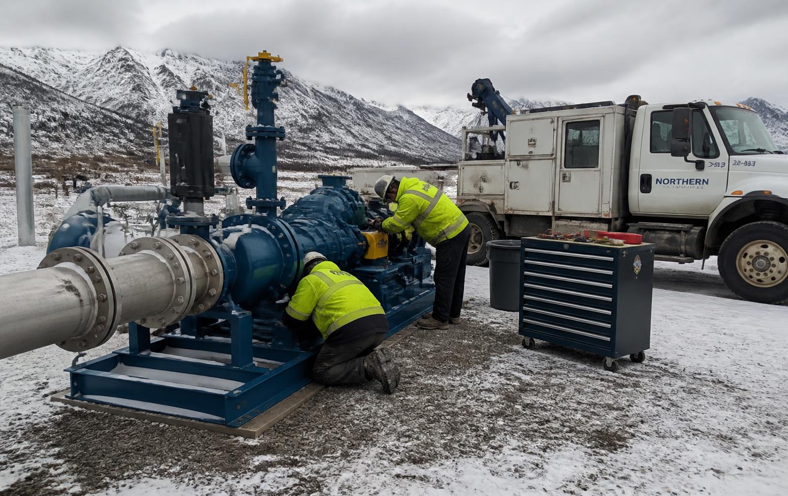 Technicians servicing an industrial pump skid at a remote Alaskan site